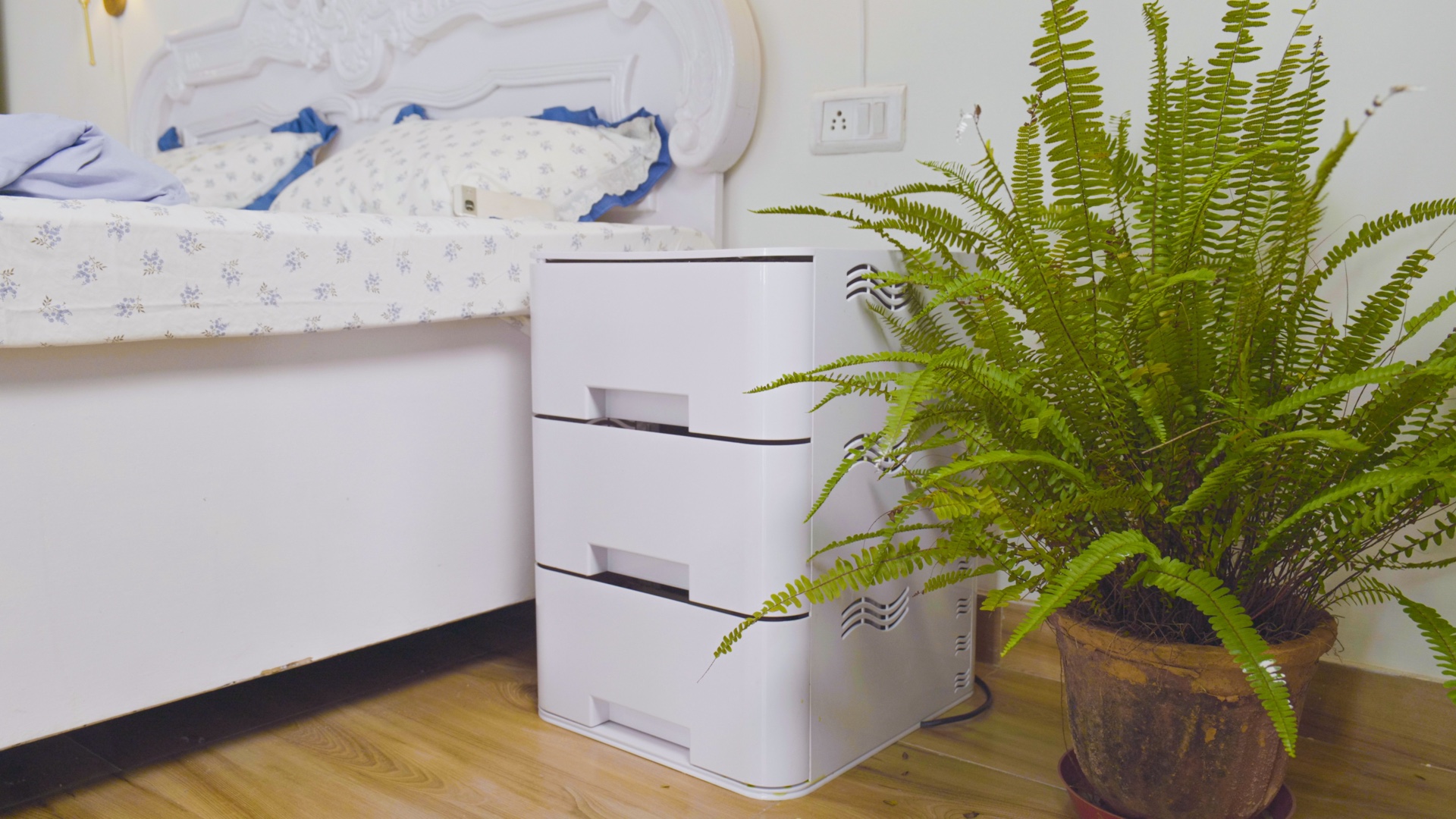 A real bedroom with greenwaterHOME beside the bed and a fern